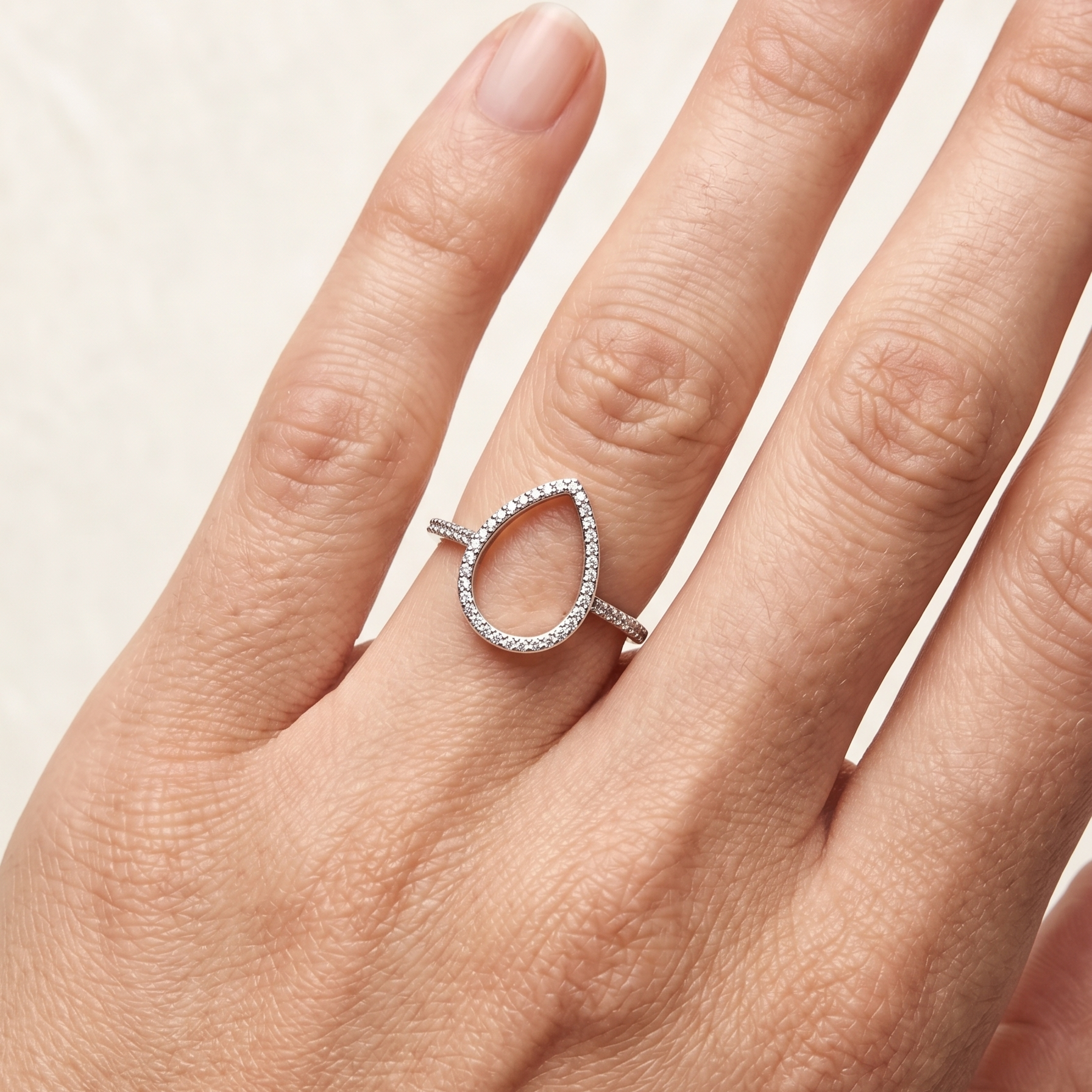Anillo con silueta de gota abierta sobre mano