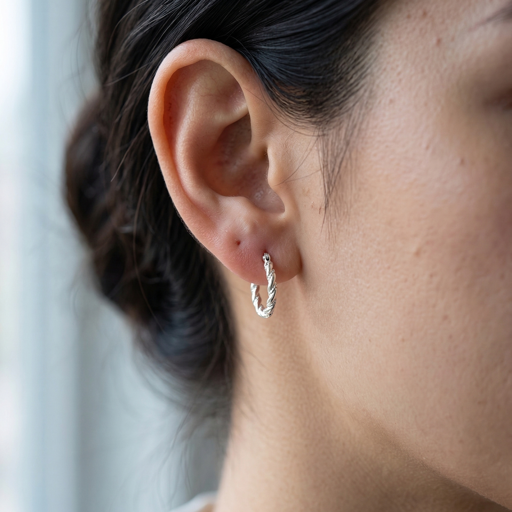 Mujer usando aretes argolla trenzada de plata 925 pequeños