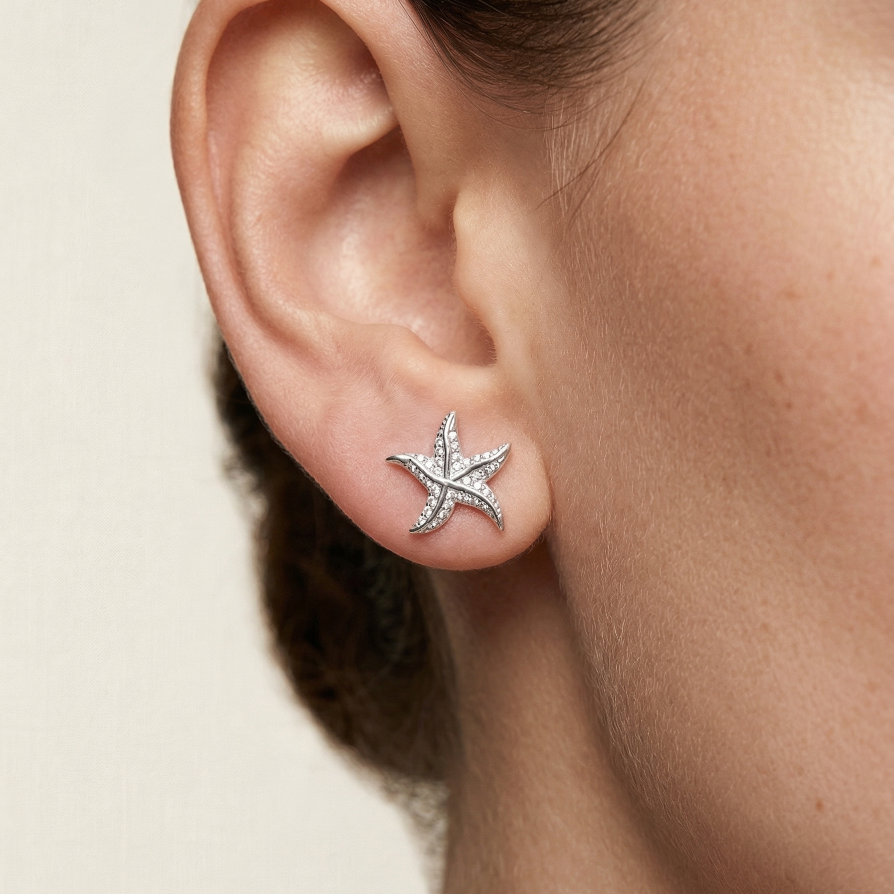 Mujer usando aretes estrella marina de plata 925 de 1 cm con acabado brillante