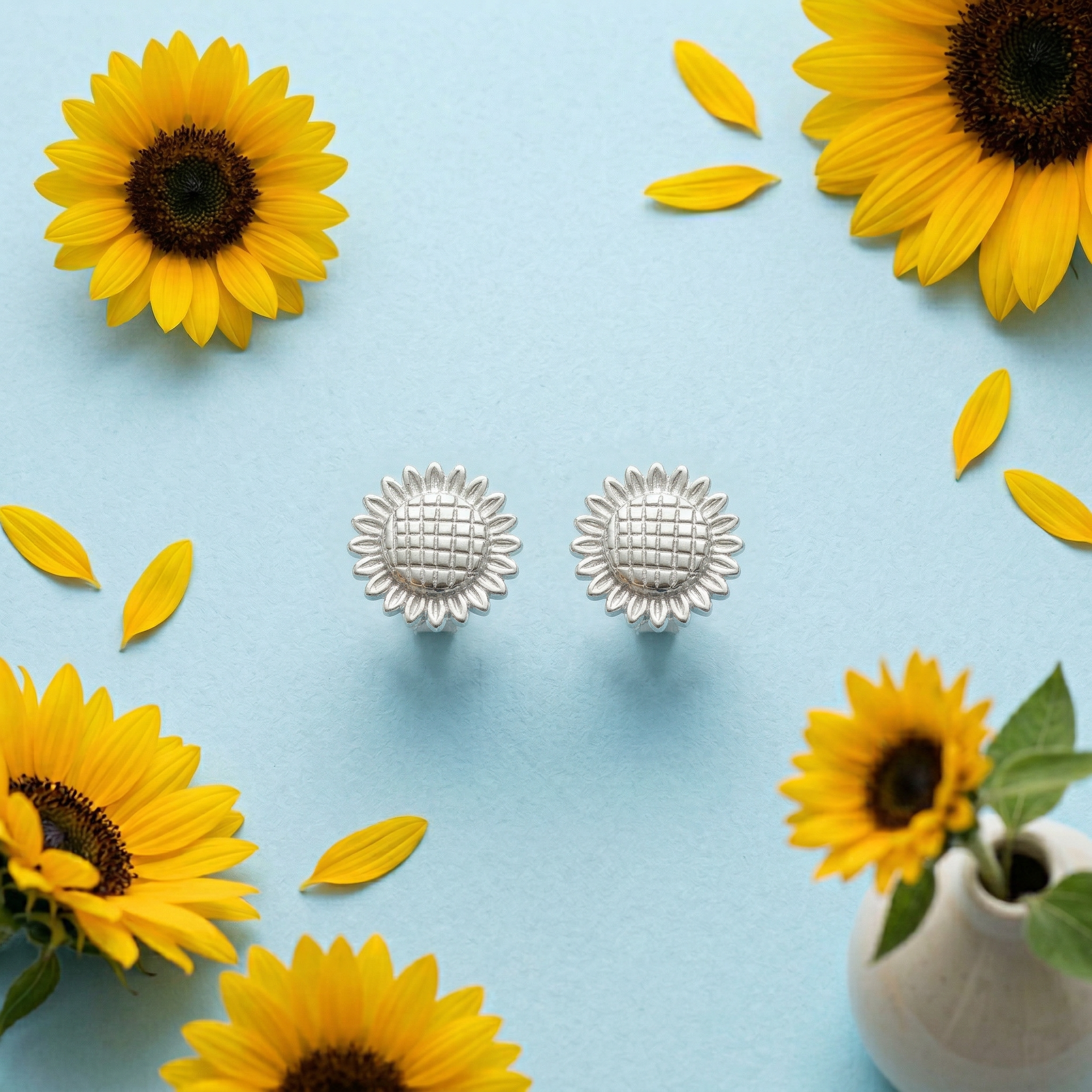 Aretes girasol mini de plata 925 sobre fondo decorativo con girasoles