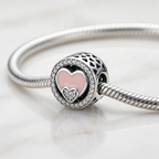 Detalle lateral de charm redondo de plata 925 con diseño romántico de corazones