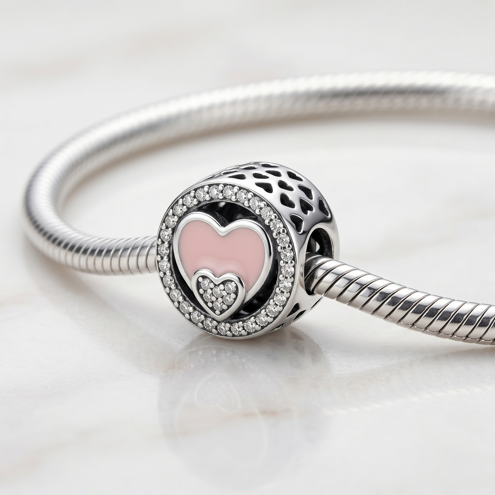Detalle lateral de charm redondo de plata 925 con diseño romántico de corazones
