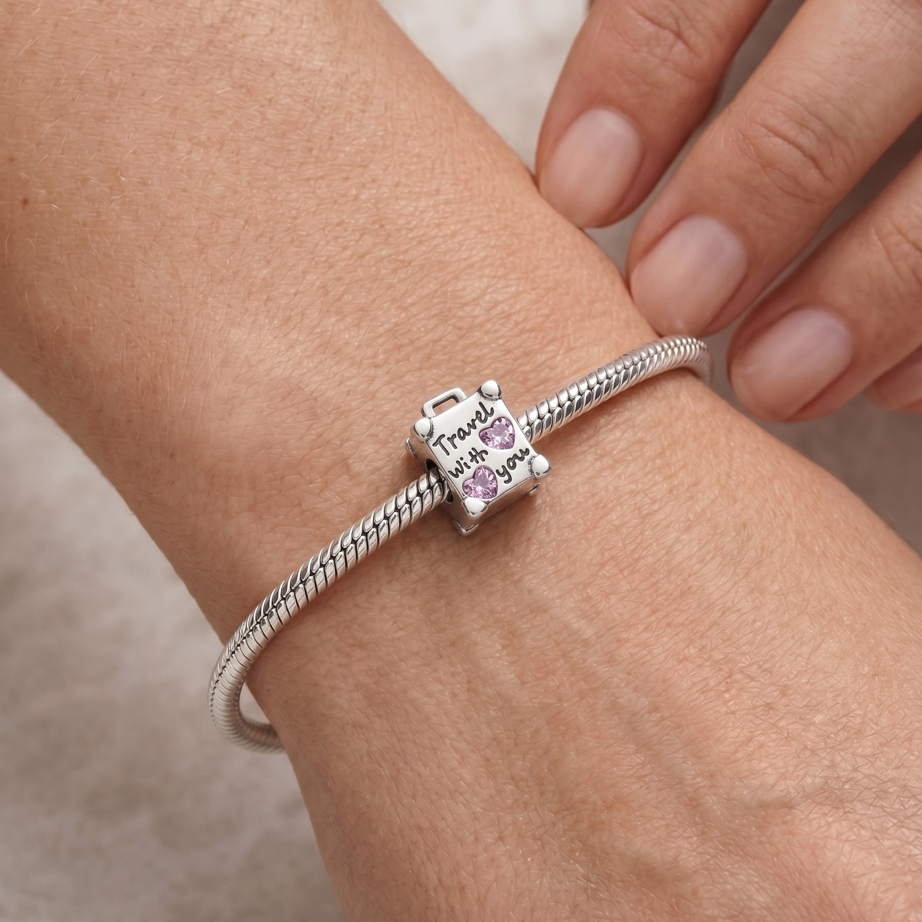 Charm maleta de plata 925 colocado en pulsera con corazones rosados y diseño de viaje