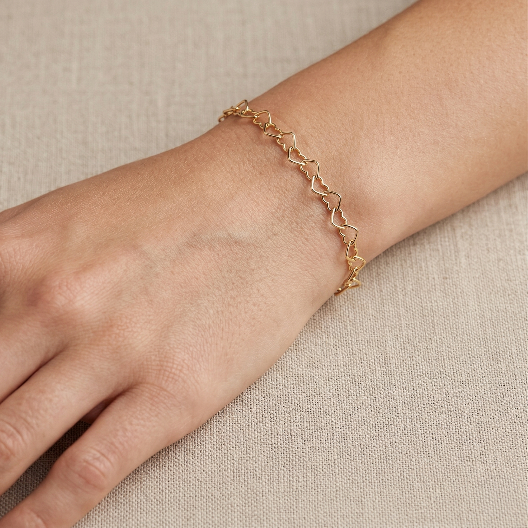 Mujer usando pulsera dorada de corazones de plata 925