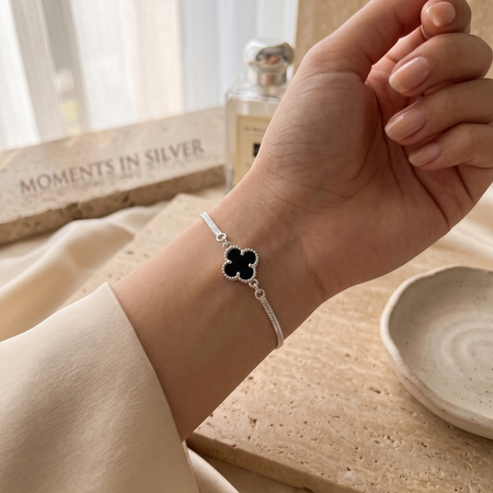 Una pulsera delicada y elegante que resalta por su contraste sutil y su detalle floral negro sofisticado.