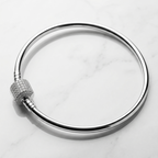 Detalle central tipo charm de 0.8 cm en pulsera rígida de plata 925