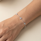 Detalle de pulsera de plata 925 con dijes tipo trébol y brillo de zircones